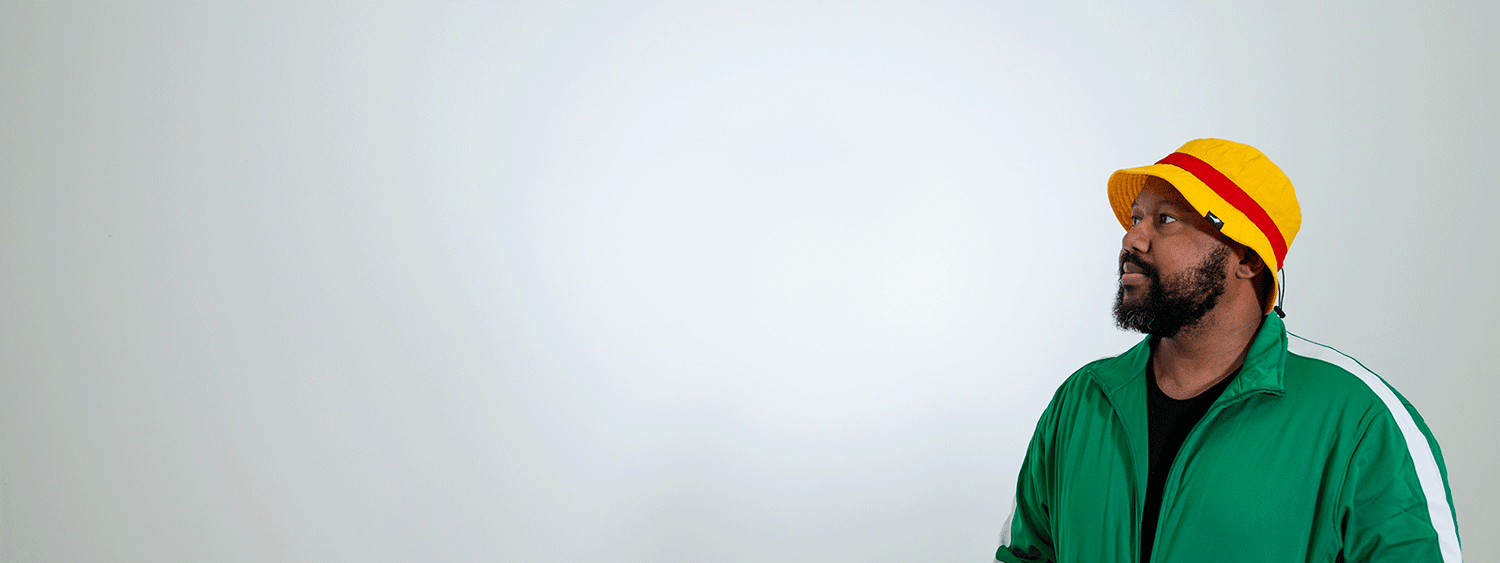 Man wearing yellow bucket hat with a red band staring to the left.